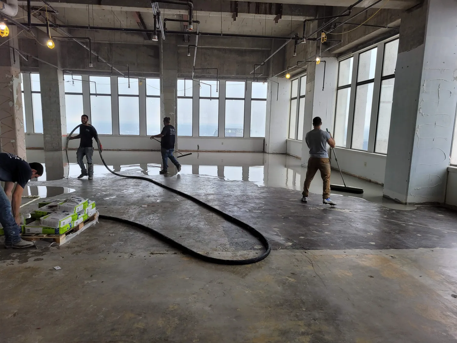 Crew walking the pump hose across the office floor toward the windows at 500 West