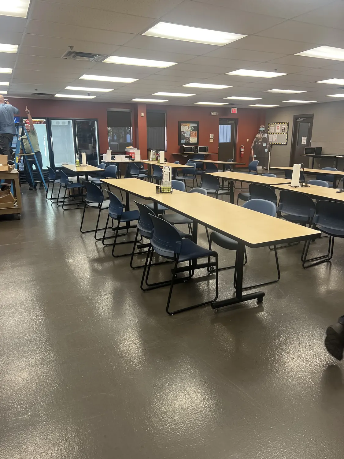 Wire Crafters breakroom before renovation, with tables and chairs on the existing grey epoxy floor